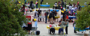 The photo is a wide shot of NECC students on the Haverhill campus outside looking at club tables and getting information.