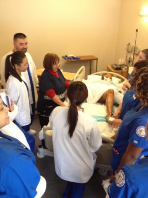 Students are gathered around a simulation of a mannequin giving birth.