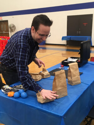 Professor mike setting up a magic trick on a table in the gym