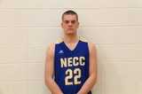 Student standing in front of white brick wall wearing a blue necc basketball uniform  