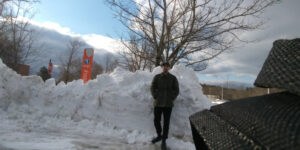 Photo of the editor in chef, Brennan Cooney standing in front of a mound of snow.