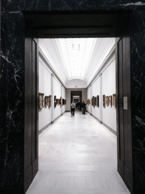long brightly lit white hallway with paintings on ether side.