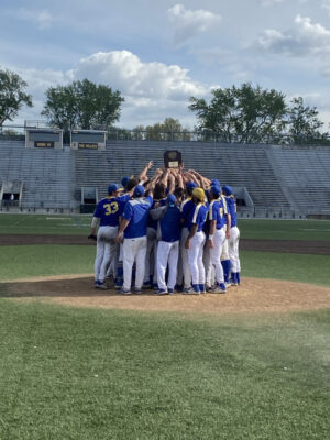 NECC Knights team holding the Northeastern District trophy in the pitching mound 