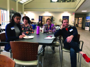 Three women and a man sit at a table in a building on the Lawrence campus. 