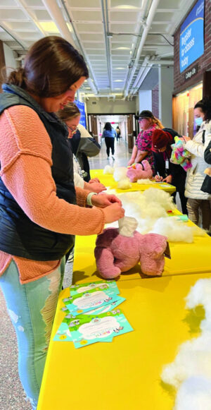 A woman stands at a table in the Spurk building and puts stuffing into a pink hippo.