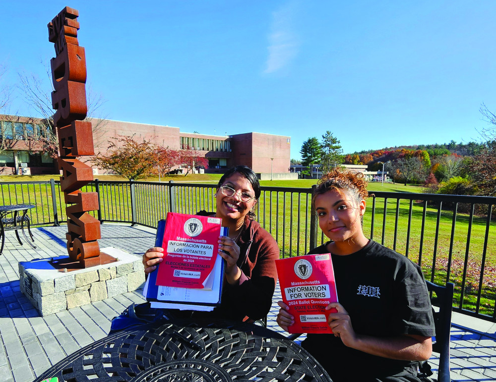 Two NECC students holding Massachusetts ballot booklets.