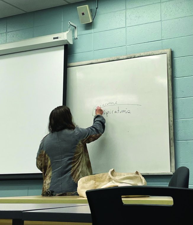 Professor Meredith Gunning is writing on the blackboard