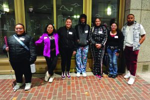 A group of students stand in front of door at Suffolk University