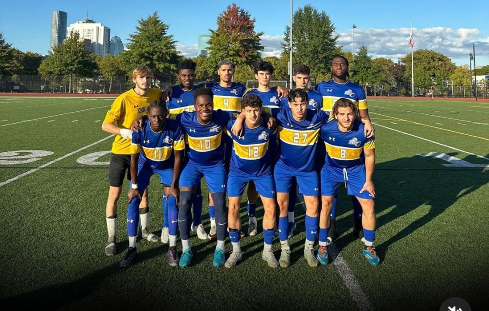 Men's soccer team poses for photo in a group on the field.