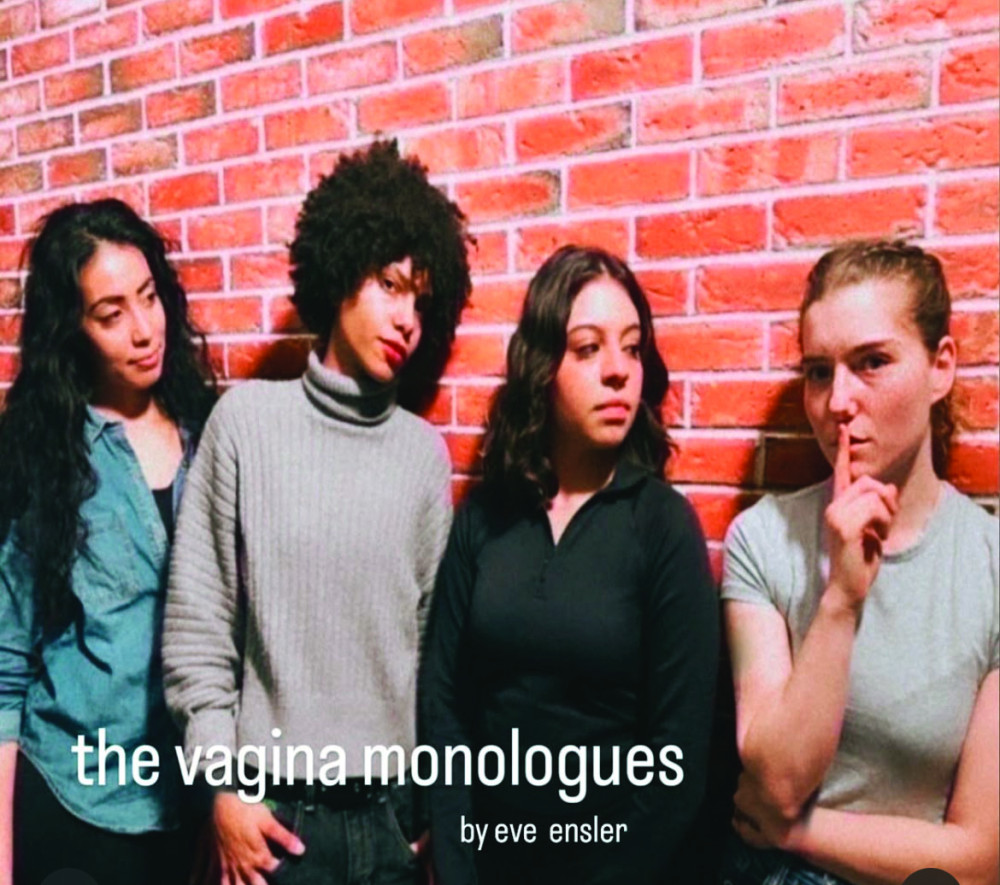 Four women stand against a brick wall looking into the camera