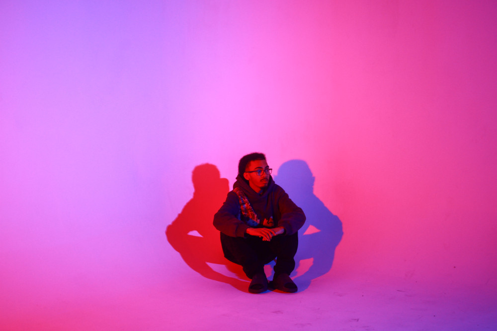 A man sitting in a pink background
