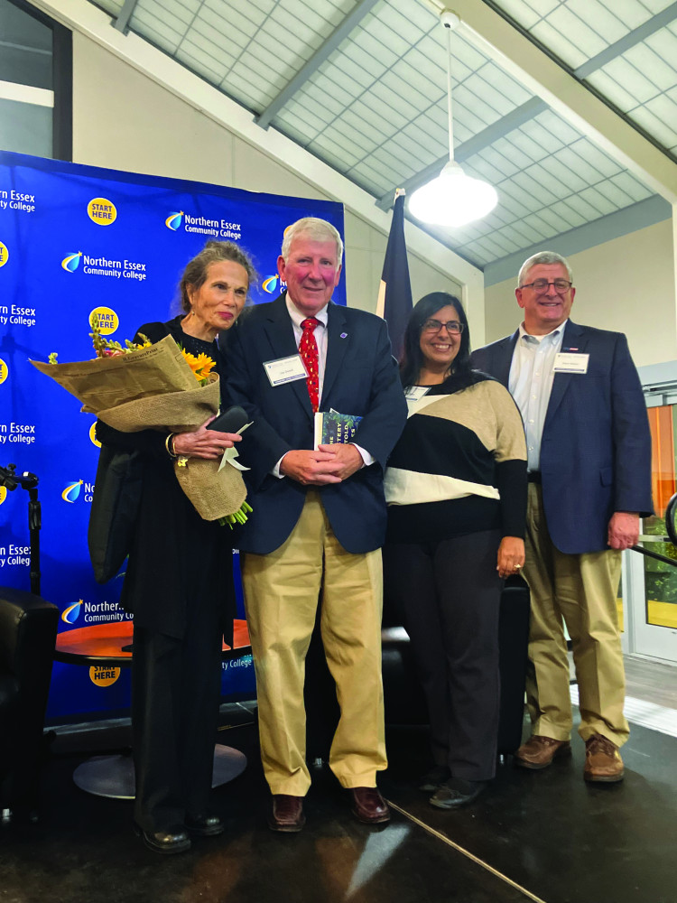 Four people standing on a stage smiling.