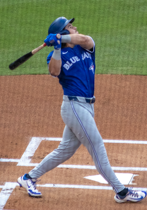Addison Barger with the Toronto Blue Jays in 2024 stands at the plate and wins at a baseball with his bat.