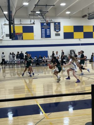 Women's basketball team players run down the court with the ball.
