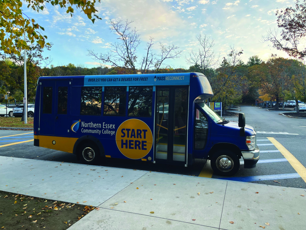 NECC shuttle bus by the curb in front of building.