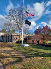 A U.S. flag and the POW/MIA flag fly at half staff.