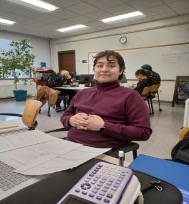 A male student sits at a desk and looks at camera