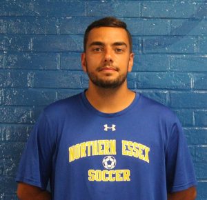 Man wearing a NECC soccer T-shirt looks at the camera.