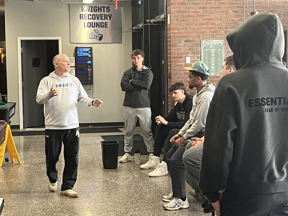 Baseball coach talks to several players in the hallway.
