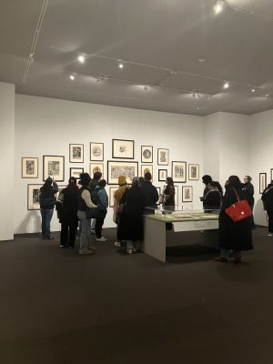 A crowd of people look at art on the wall at the Museum of Fine Arts in Boston. 