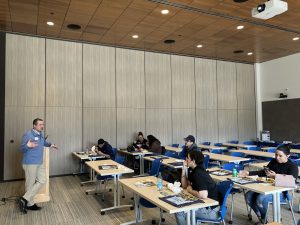 A man stands in a classroom and talks to students