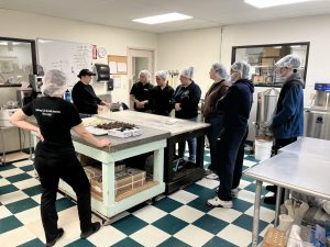PACE TRIO staff on Van Otis chocolate factory tour. Men and women stand around a table looking at chocolate.