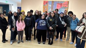 A group of students, staff and faculty in a group photo, standing and smiling at the camera.