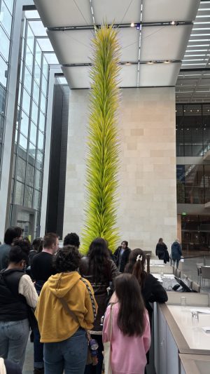 A group of people walk through a corridor with a large green plant in the Museum of Fine Arts