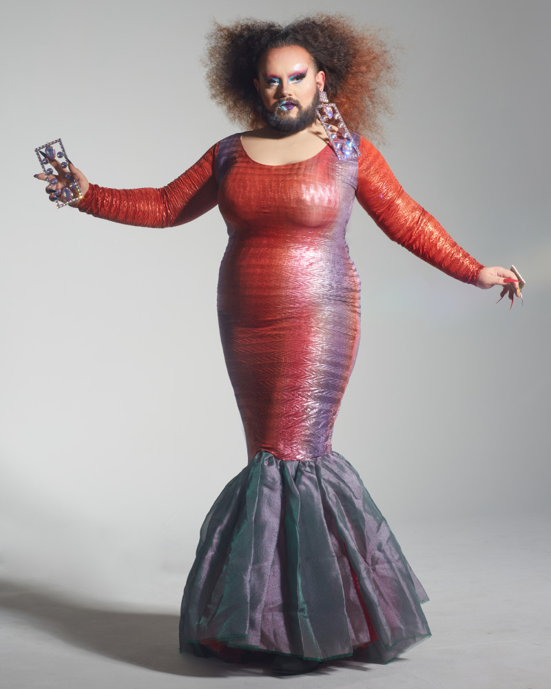 A drag queen with a beard in a mermaid dress.